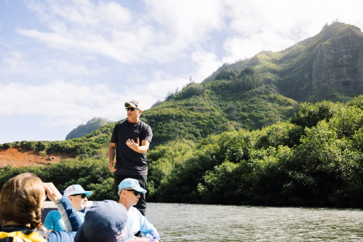Guide sharing local history during a Hawaiian canoe ride on the Huleʻia River, Kauaʻi