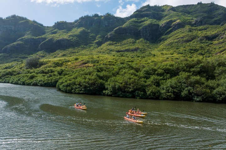 Kayakers paddling the Huleʻia River beneath the Haʻupu Mountain Range on Kauaʻi