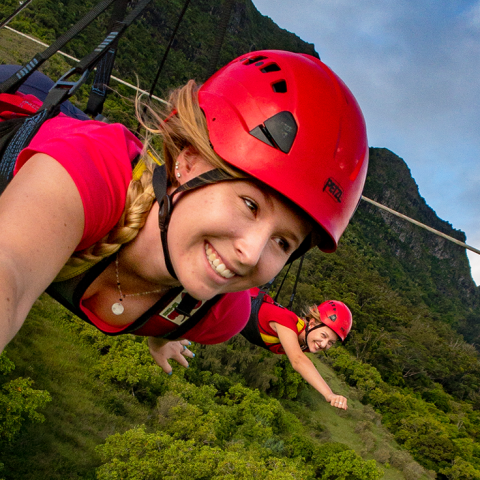 Two girls launching on the FlyLine, the longest zipline in Hawaiʻi, at Outfitters Kauaʻi.