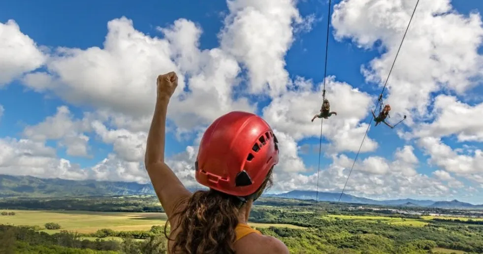 Guest cheering from the Kipu Ranch launch deck as friends ride the FlyLine on the Nui Kauaʻi Zipline tour.