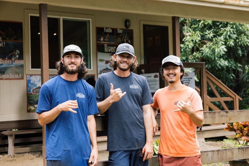 Outfitters Kauai guides throwing shakas at Kipu Ranch zipline headquarters, showcasing friendly local staff and authentic Kauai adventure culture.