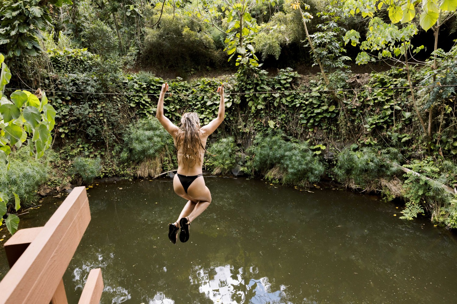 Guest riding the Water Zipline into Bamboo Pool at Outfitters Kauai on Kauaʻi