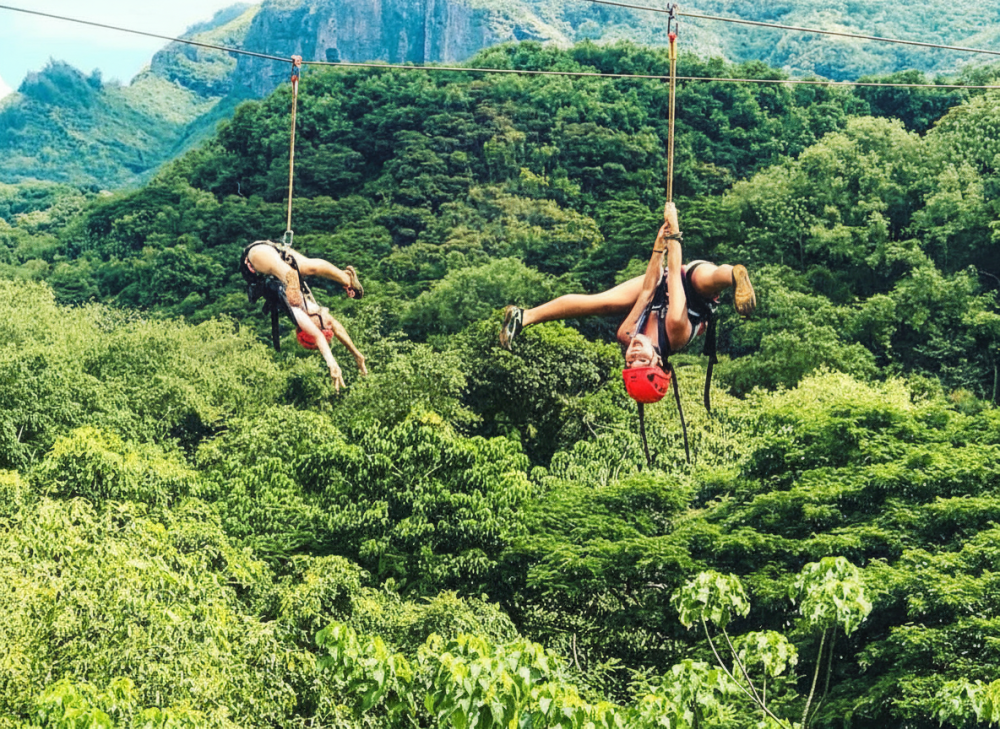 Two people ziplining upside down over lush green forest on Kipu Ranch on the Adrenaline Zipline Tour with Outfitters Kauai.