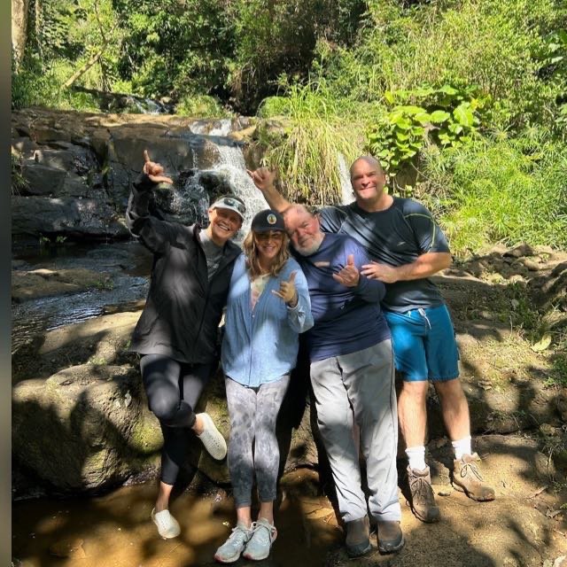 Guests smiling at Nui Kauai Zipline waterfall stop during guided zipline adventure in lush Kauai rainforest