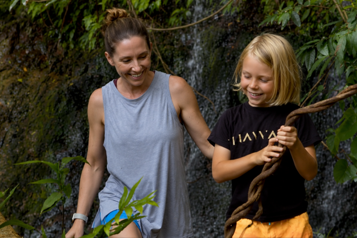 Woman and child smile by a waterfall on the Kipu Falls and Treehouse Hike by Outfitters Kauai